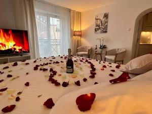 Una cama con una botella de vino y rosas. en Louis & Elza Old Town Romantic apartments, en Wroclaw