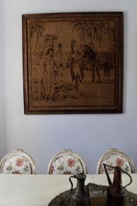 a painting hanging on a wall above a table with chairs at Casa Xanadu Seville - Boutique rooms with terraces in Seville