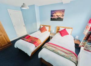 two beds in a room with blue walls at Dapps Hill Haven - between Bristol and Bath, both 9 mins by train! in Keynsham