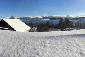 um campo coberto de neve com um celeiro ao fundo em Spacious modern apartment, close to nature em Tromsø