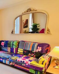a colorful couch in a living room with a mirror at Dapps Hill Haven - between Bristol and Bath, both 9 mins by train! in Keynsham