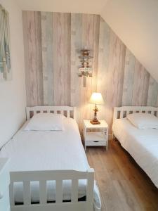 a bedroom with two beds and a table with a lamp at Hôtel Restaurant Ferme de la Grande Cour in Honfleur