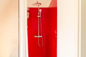 La salle de bains est pourvue d'une douche rouge et d'un mur rouge. dans l'établissement Luxuriöses Penthouse mit Dachterrasse & Massagesessel EM-APARTMENTS DEUTSCHLAND, à Bielefeld