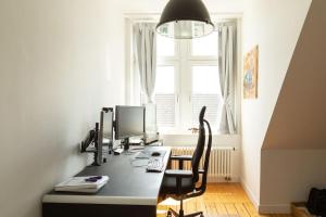 ein Büro mit einem Schreibtisch mit einem Computer und einem Stuhl in der Unterkunft Luxuriöses Penthouse mit Dachterrasse & Massagesessel EM-APARTMENTS DEUTSCHLAND in Bielefeld