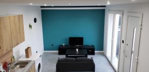 ein Wohnzimmer mit einem Sofa und einer blauen Wand in der Unterkunft La Plume d'Or - Wifi - Parking Privé in Lens