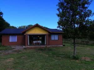 une petite maison dans une cour avec un arbre dans l'établissement Cabaña Hijuela Colga, à Villarrica