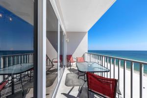 einen Balkon mit Tischen, Stühlen und Meerblick in der Unterkunft Windemere 904 Pool Side Cabana Included! in Perdido Key