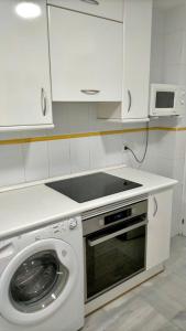a kitchen with a washing machine and a microwave at Entre hoyos y la playa Grupo AC Gestion in Novo Sancti Petri