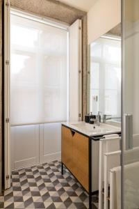 La salle de bains est pourvue d'un lavabo, d'une fenêtre et d'un sol en damier. dans l'établissement Bright studio with terrace, à Porto