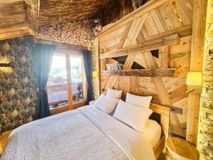 1 dormitorio con 1 cama y pared de madera en Studio Lachat - Centre village, vue montagnes - AravisTour, en Saint-Jean-de-Sixt