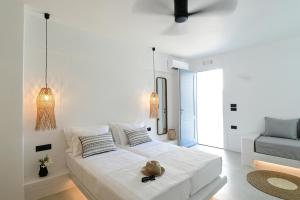 a white bedroom with a bed with a hat on it at Ios Art Studios & Luxury Apartments in Ios Chora