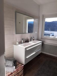 La salle de bains est pourvue d'un lavabo blanc et d'un miroir. dans l'établissement Seeblick Millstatt, à Millstatt
