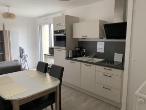 a kitchen with white cabinets and a table with a dining room at Charmant T2 en centre-ville avec balcon, parking privé et équipements bébé à Fort-Mahon-Plage - FR-1-482-99 in Fort-Mahon-Plage