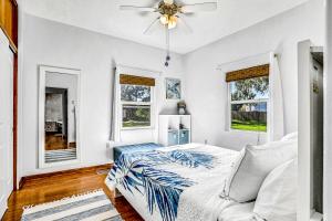 a white bedroom with a bed and windows at River Cottage in Edgewater