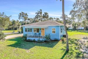 a blue house with a palm tree in a yard at River Cottage in Edgewater