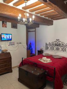 um quarto com uma cama vermelha e uma televisão em Affittacamere Mirella em Gubbio