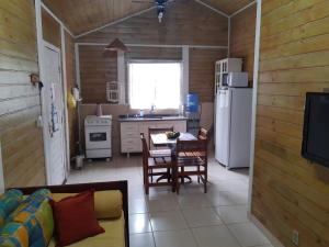 a kitchen and dining room with a table and a refrigerator at Casa Condomínio Boiçucanga in Boicucanga