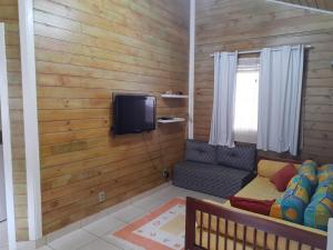 ein Wohnzimmer mit Sofa und Fernseher in der Unterkunft Casa Condomínio Boiçucanga in Boicucanga