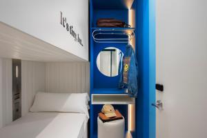 Habitación pequeña con cama y pared azul en COEO Pod Hostel - Part of COEO Experience en Málaga