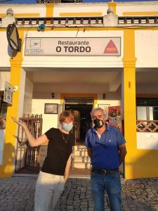 two people wearing masks standing in front of a store at Alojamento O Tordo in Torrão