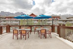 a patio with tables and chairs and blue umbrellas at Modern Nordic 2 Bedroom Mountain View Condo in Canmore