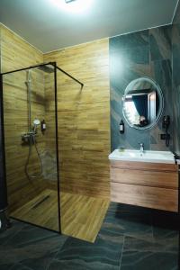 ein Bad mit einer Dusche, einem Waschbecken und einem Spiegel in der Unterkunft Georgia Chalet in Dorna-Arini