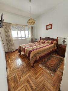 1 dormitorio con 1 cama grande y suelo de madera en La Perla 4toA en Mar del Plata