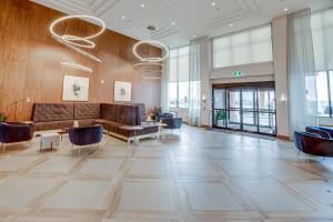a lobby with a couch and tables and windows at Sandman Signature Saskatoon South Hotel in Saskatoon