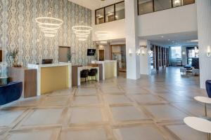 a lobby with tables and chairs in a building at Sandman Signature Saskatoon South Hotel in Saskatoon