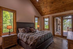a bedroom with a bed with a wooden ceiling and windows at Clouds Rest at Eagles Nest in Beech Mountain