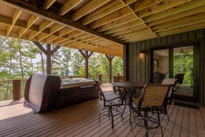 a screened in deck with a hot tub and a table and chairs at Clouds Rest at Eagles Nest in Beech Mountain