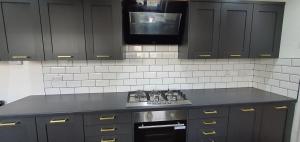 a kitchen with black cabinets and a stove and a tv at Glenfield Park House in Leicester