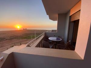 a balcony with a table and chairs and the sunset at Agadir well in Mirleft
