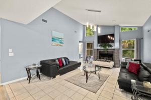sala de estar con muebles de cuero negro y chimenea en Modern Vacation Home w/ Heated Pool 10min to the Beach en Palm Coast