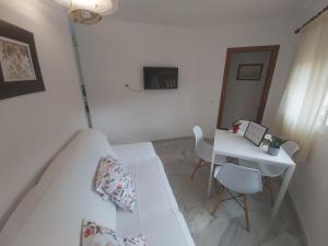 a white bedroom with a bed and a desk at Apartamento Sostoa 4 in Málaga