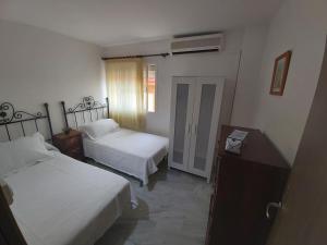 a hotel room with two beds and a window at Apartamento Sostoa 4 in Málaga