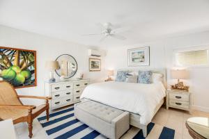 ein weißes Schlafzimmer mit einem Bett und einem Stuhl in der Unterkunft Casa Del Mar in Key Colony Beach