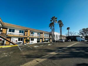 un aparcamiento frente a un hotel con palmeras en Casa Blanca Express & Suites Cypress Buena Park - Anaheim Area en Cypress