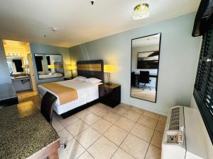 a hotel room with a bed and a mirror at Casa Blanca Express & Suites Cypress Buena Park - Anaheim Area in Cypress