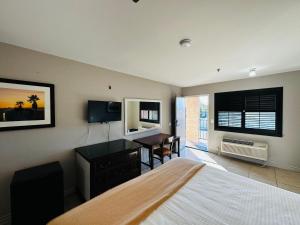 a bedroom with a bed and a desk and a table at Casa Blanca Express & Suites Cypress Buena Park - Anaheim Area in Cypress