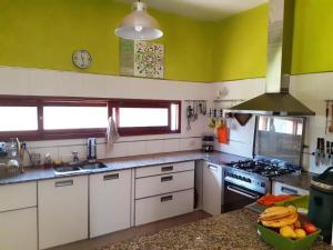 una cocina con armarios blancos y paredes verdes en Posada Fresnos Dorados en Maipú