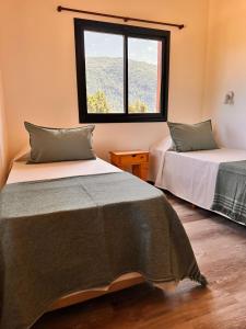 two beds in a room with a window at Complejo Camino al Lago in Lago Puelo