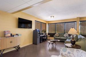 a waiting room with a couch and a tv in a room at SureStay Hotel by Best Western St Pete Clearwater Airport in Clearwater