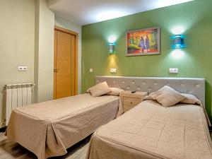 two beds in a room with green walls at Hostal Real Aranjuez in Aranjuez