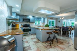 una gran cocina con armarios azules y un bar con taburetes en Poconos Home with Marshall's Creek Views - Nearby Ski, HUGE Private 6 Bedroom Home!, en East Stroudsburg