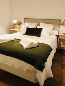 Elle comprend un grand lit avec des draps blancs et une couverture verte. dans l'établissement Petit apartment LOS REMEDIOS, à Séville