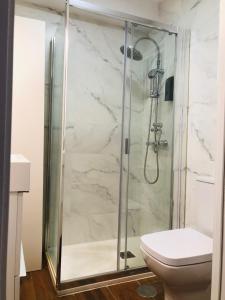 La salle de bains est pourvue d'une douche en verre et de toilettes. dans l'établissement Petit apartment LOS REMEDIOS, à Séville