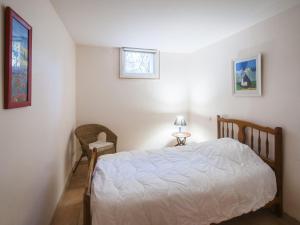 1 dormitorio con 1 cama blanca y 1 silla en Villa Soulac-sur-Mer, 9 pièces, 11 personnes - FR-1-648-42, en Soulac-sur-Mer