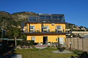 ein gelbes Haus mit Balkon darüber in der Unterkunft Villa Le Logge in Ventimiglia