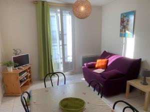 a living room with a purple couch and a table at Appartement Mont-Dore, 2 pièces, 4 personnes - FR-1-415-129 in Le Mont-Dore